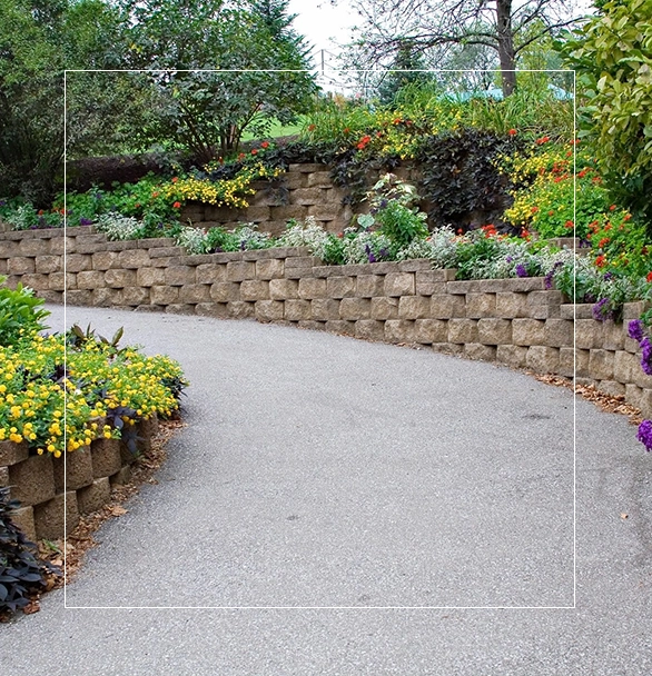 A curved driveway with a flower garden in the background.