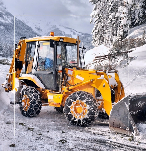 A yellow tractor with snow chains on the front.