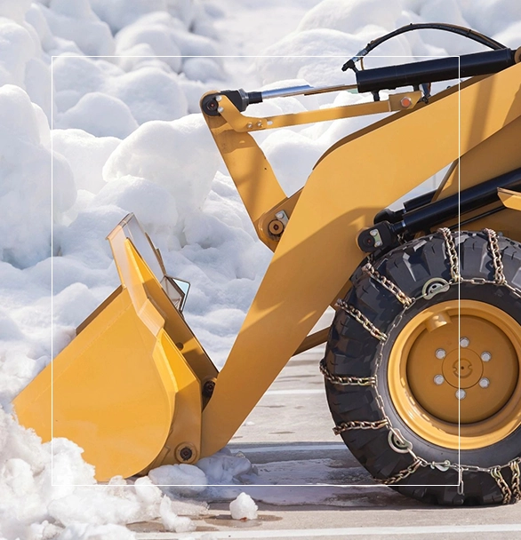 A yellow wheel loader is parked in the snow.