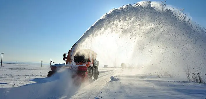 A snow plow truck is blowing the snow off of it.