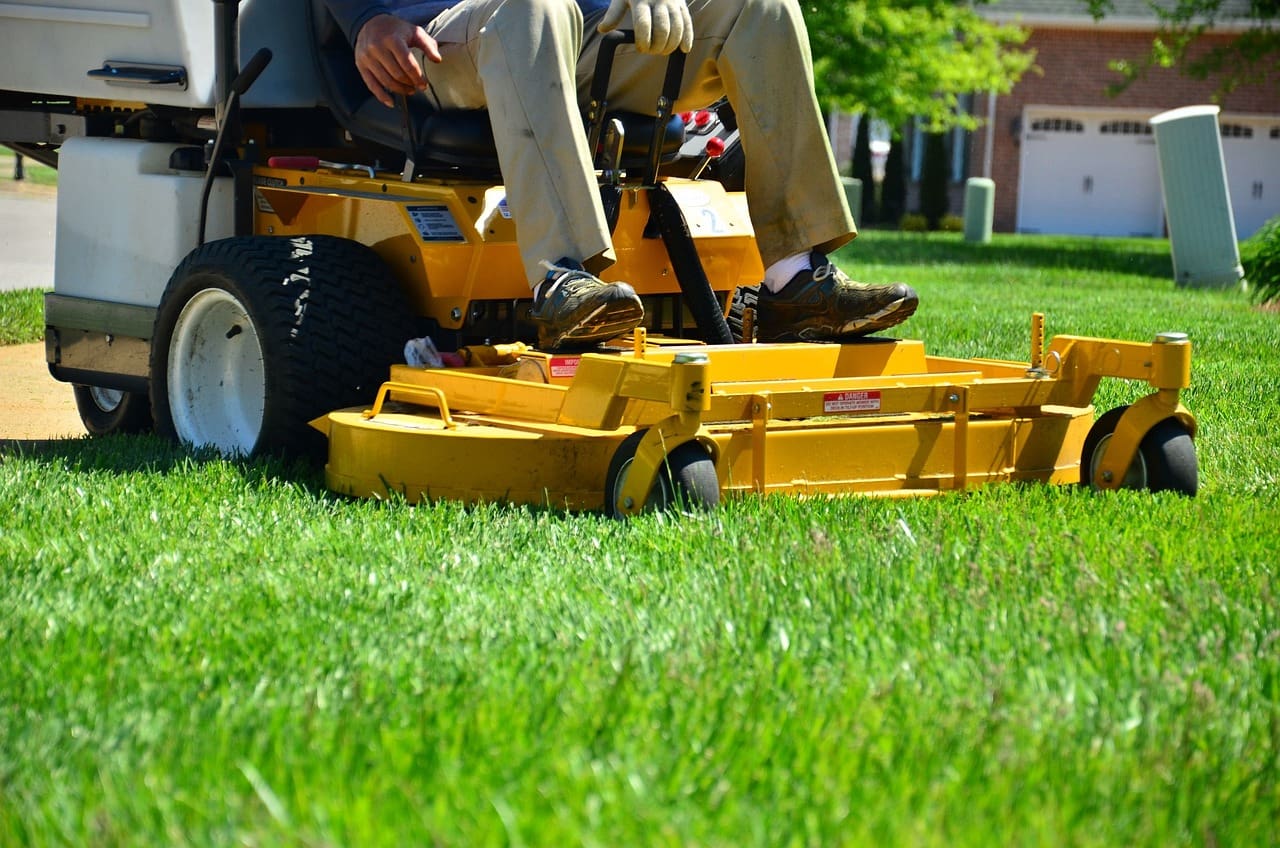 A person on a yellow lawn mower in the grass.